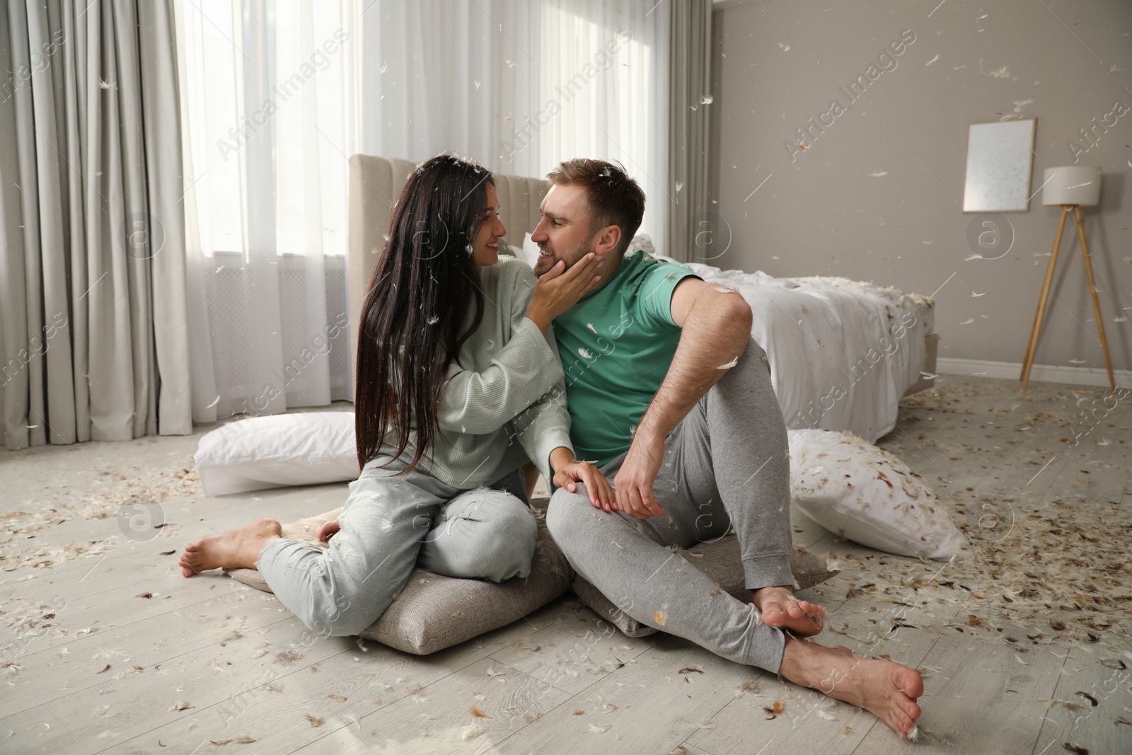 Photo of Happy young couple resting after fun pillow fight in bedroom