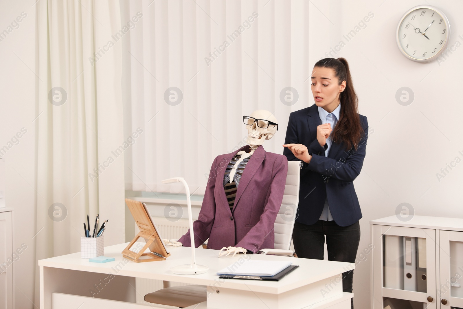 Photo of Young woman near human skeleton in office