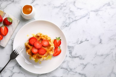 Delicious Belgian waffles with strawberries and honey on white marble table, top view. Space for text