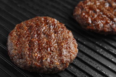 Photo of Prepared meat cutlets for burger on grill, closeup