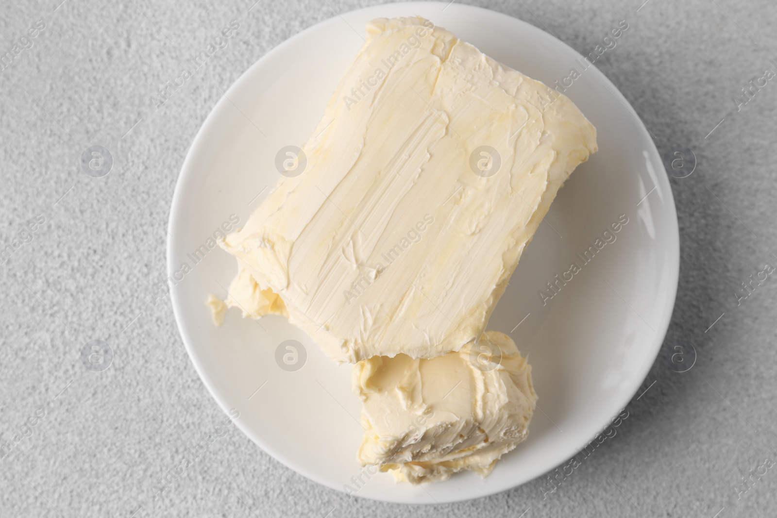 Photo of Plate with tasty homemade butter on white textured table, top view