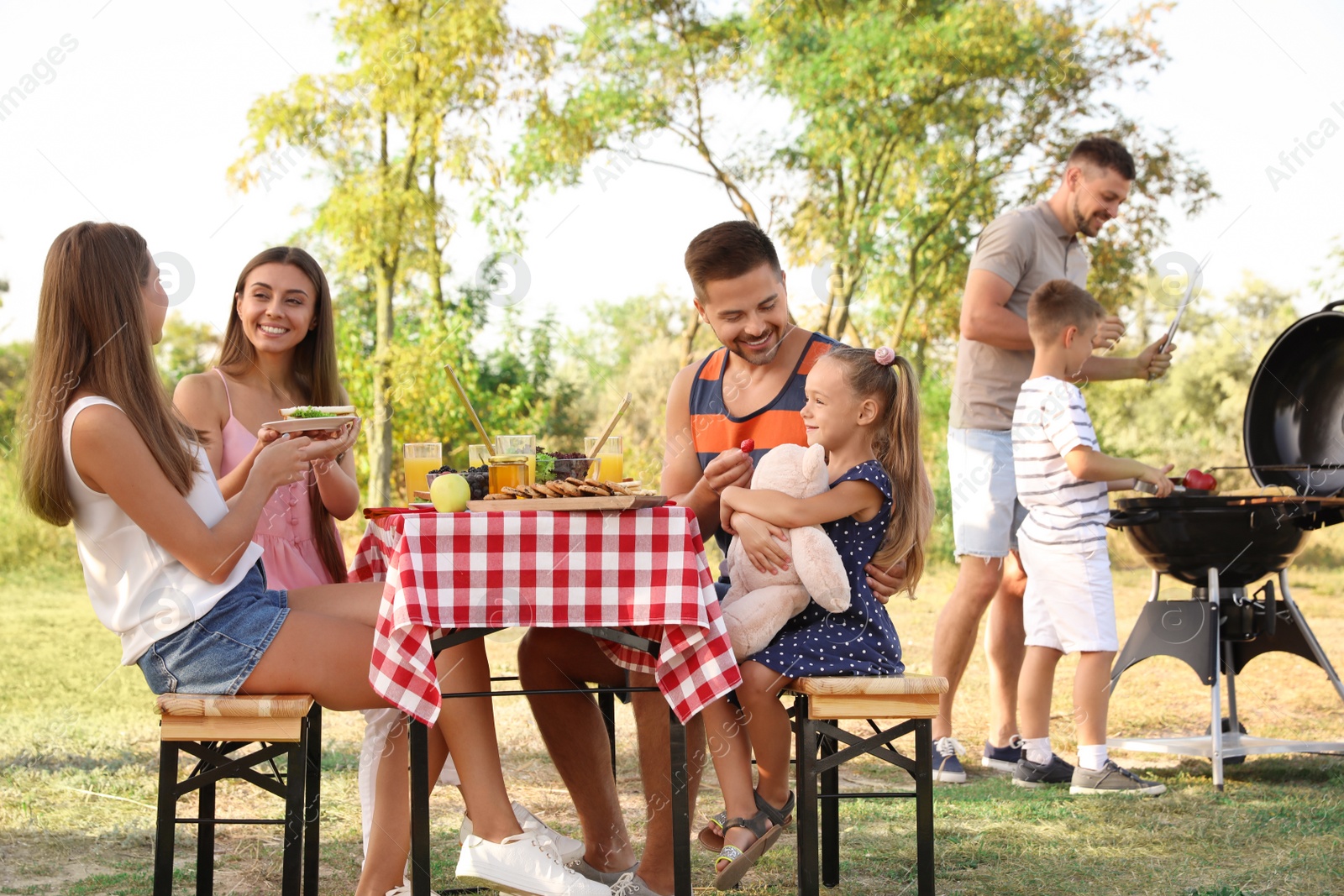 Photo of Happy families with little children having picnic in park