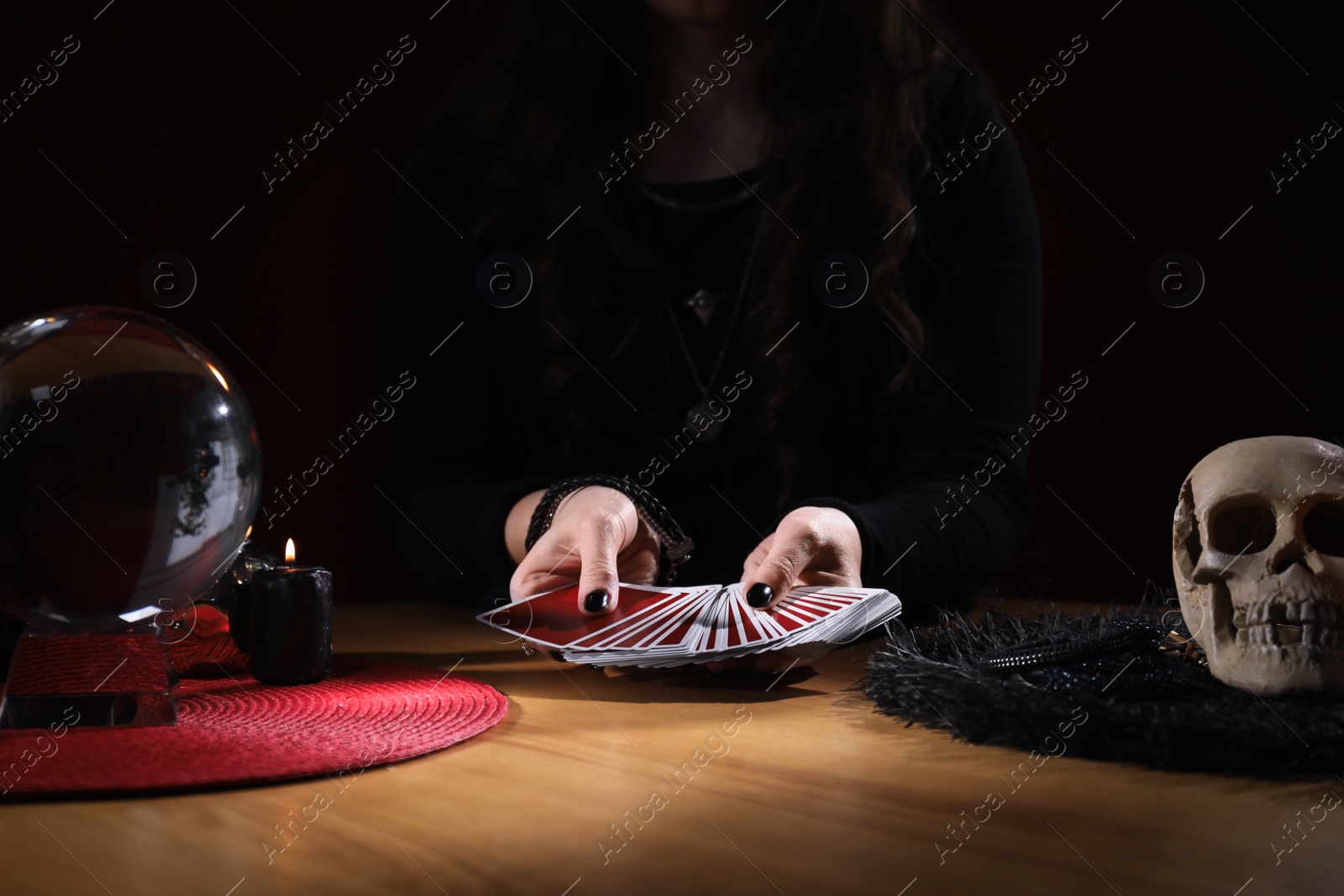 Photo of Soothsayer predicting future with cards at table indoors, closeup