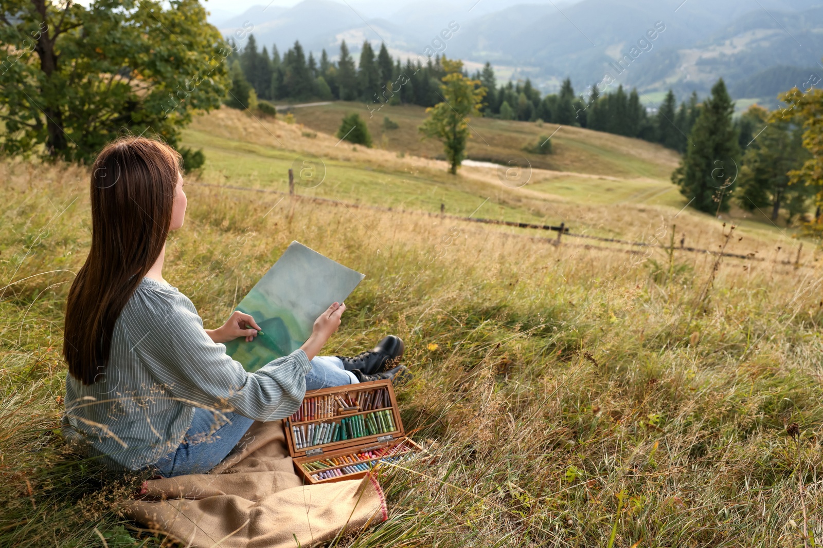 Photo of Young woman drawing landscape with soft pastels in nature. Space for text