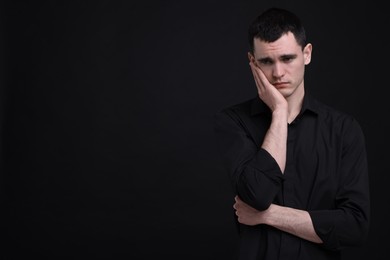 Photo of Portrait of sad man on black background, space for text