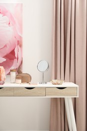 Dressing table with mirror, cosmetic products, jewelry and burning candles in makeup room