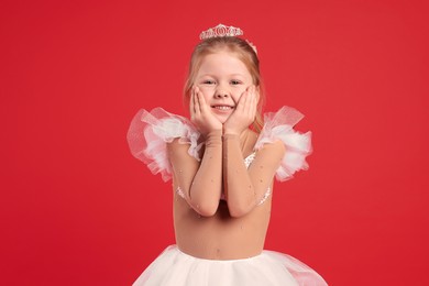 Photo of Cute girl in fairy dress with diadem on red background. Little princess