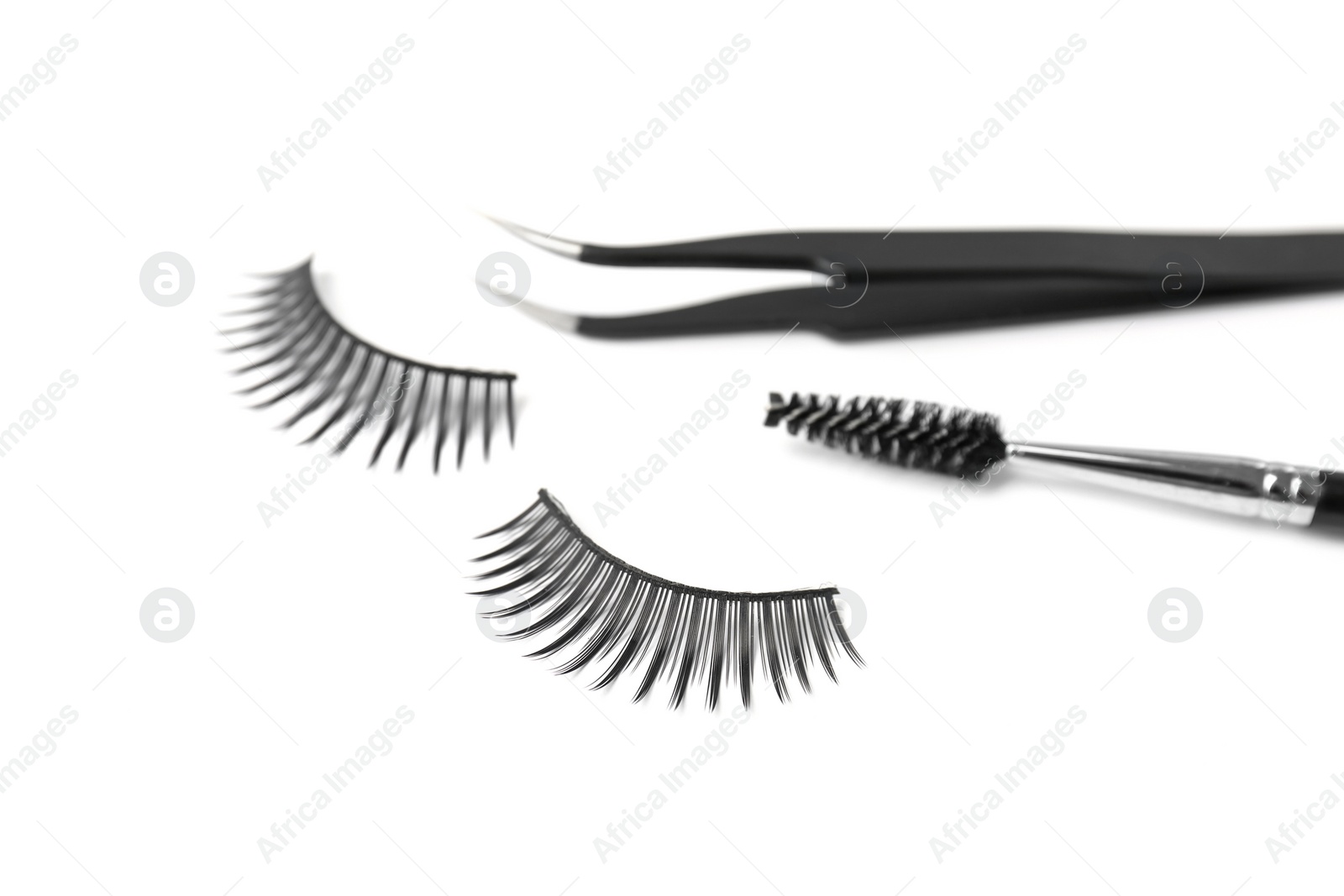 Photo of Mascara brush, tweezers and false eyelashes on white background