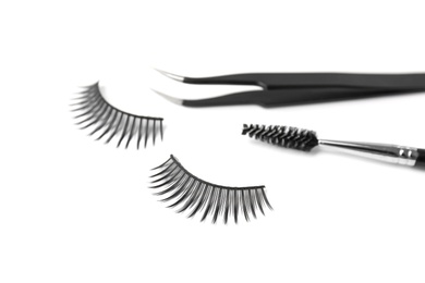 Photo of Mascara brush, tweezers and false eyelashes on white background