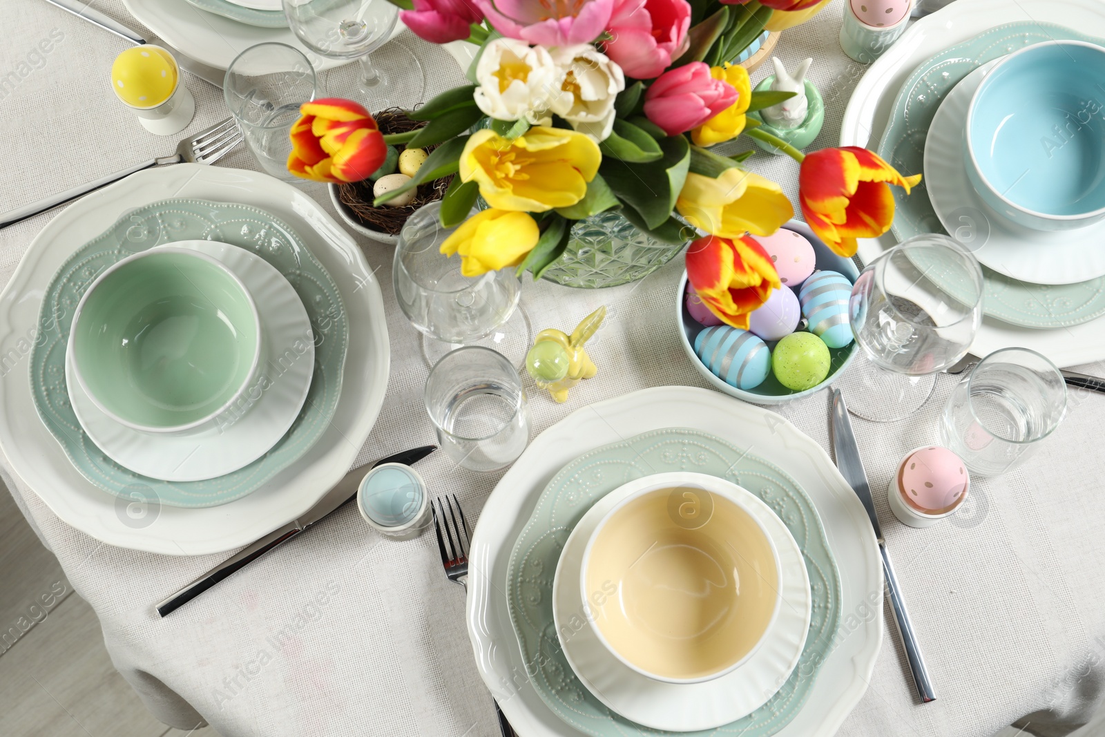 Photo of Festive Easter table setting with beautiful flowers and painted eggs, top view