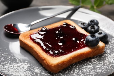 Photo of Delicious toast with jam and blueberries on plate, closeup