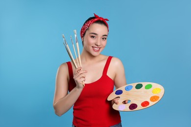 Woman with painting tools on light blue background. Young artist