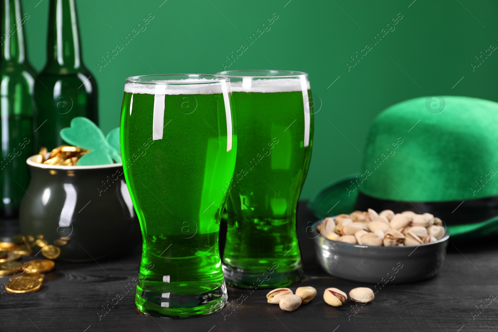 Photo of St. Patrick's day party. Green beer, leprechaun hat, pot of gold and pistachios on wooden table