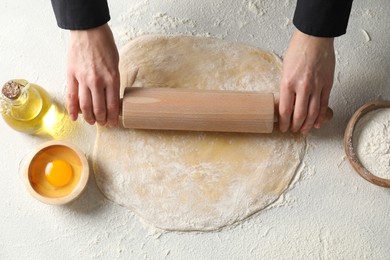 Woman rolling raw dough at table, closeup