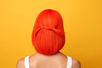 Photo of Young woman with bright dyed hair on orange background, back view