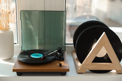 Vinyl records and player on white window sill