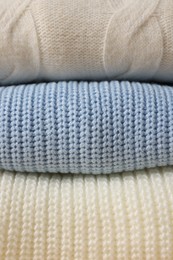Photo of Stack of casual warm sweaters as background, closeup view