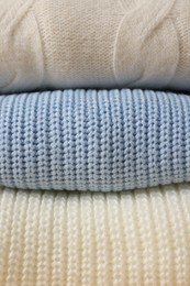 Stack of casual warm sweaters as background, closeup view