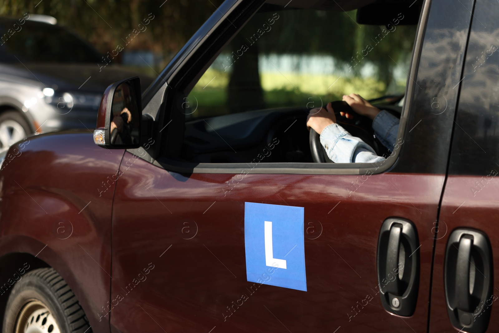Photo of Learner driver driving car with L-plate, view from outside. Driving school
