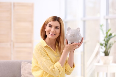 Photo of Portrait of woman with piggy bank at home