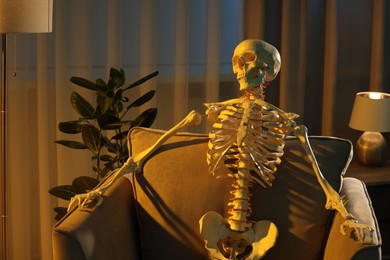 Photo of Waiting concept. Human skeleton sitting in armchair indoors