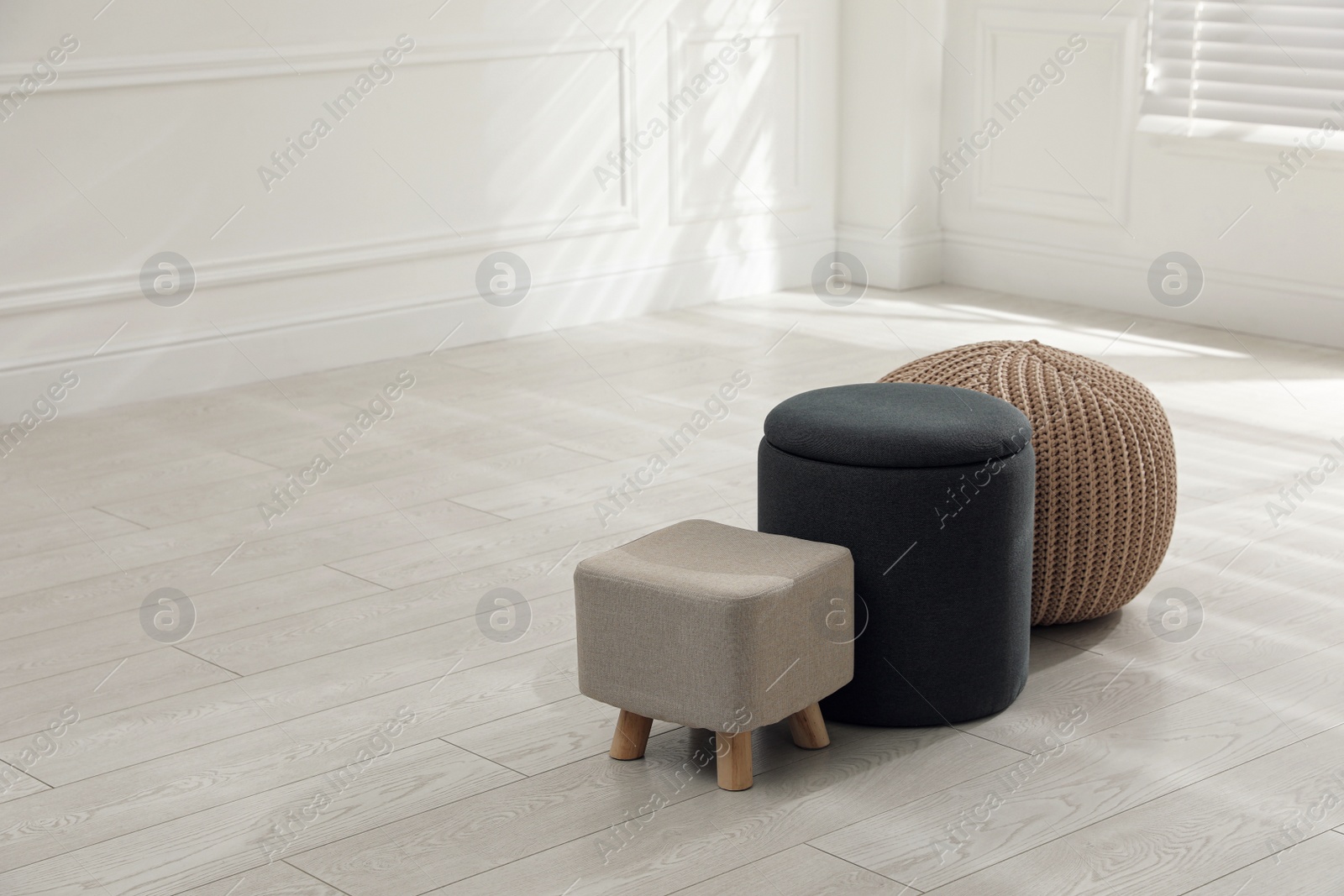 Photo of Different stylish pouf and ottomans in room, space for text