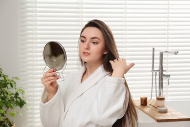 Beautiful woman looking in mirror in bathroom
