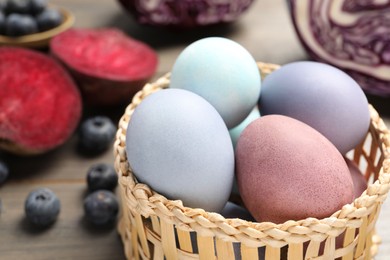 Photo of Colorful Easter eggs painted with natural dyes in wicker bowl, closeup