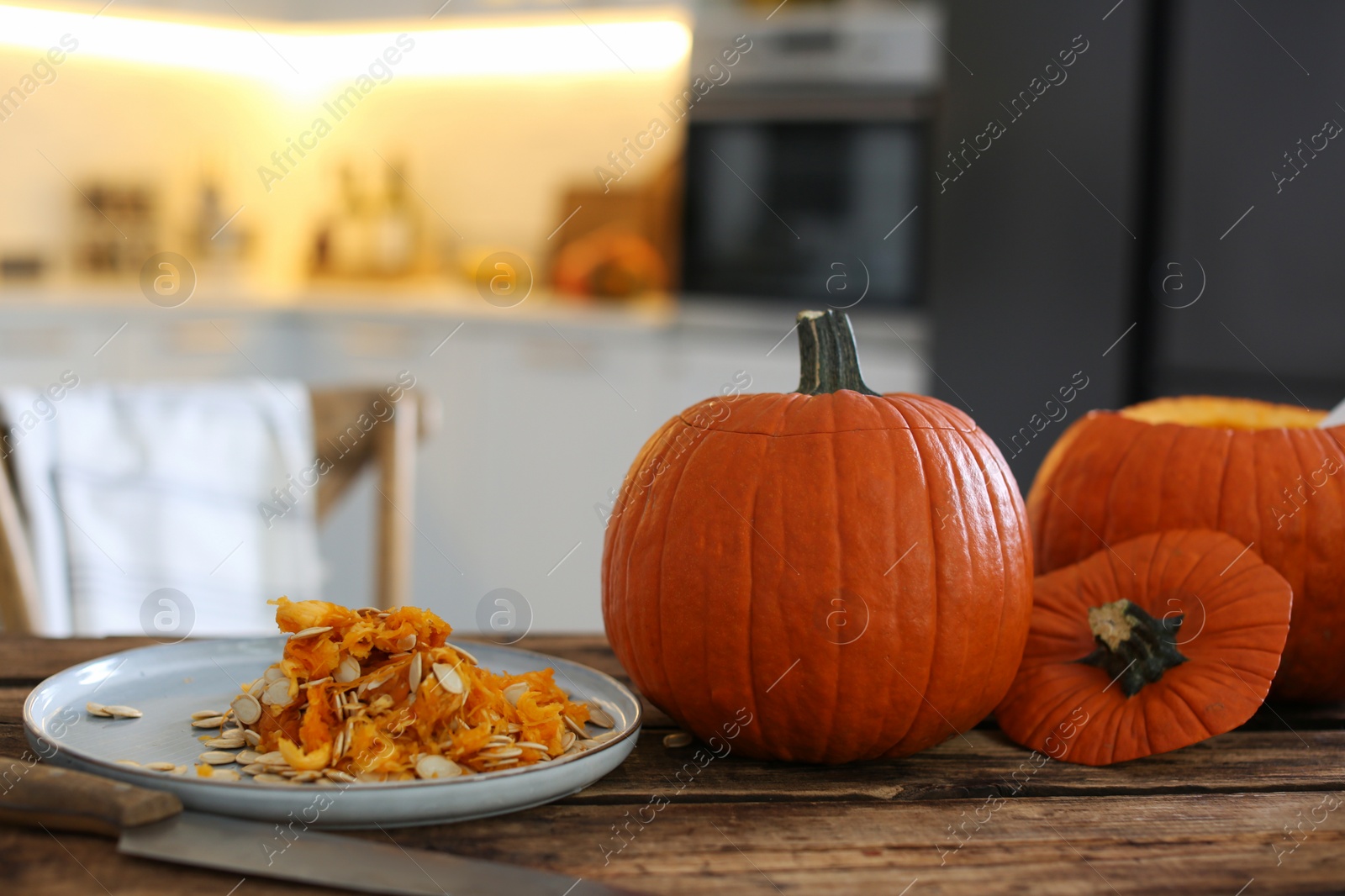 Photo of Fresh ripe pumpkins on wooden table in kitchen, space for text. Halloween celebration