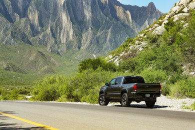 Photo of Black car near beautiful mountains and road outdoors