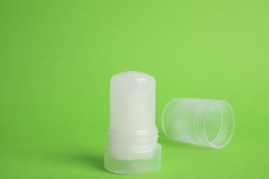 Photo of Natural crystal alum stick deodorant and cap on green background