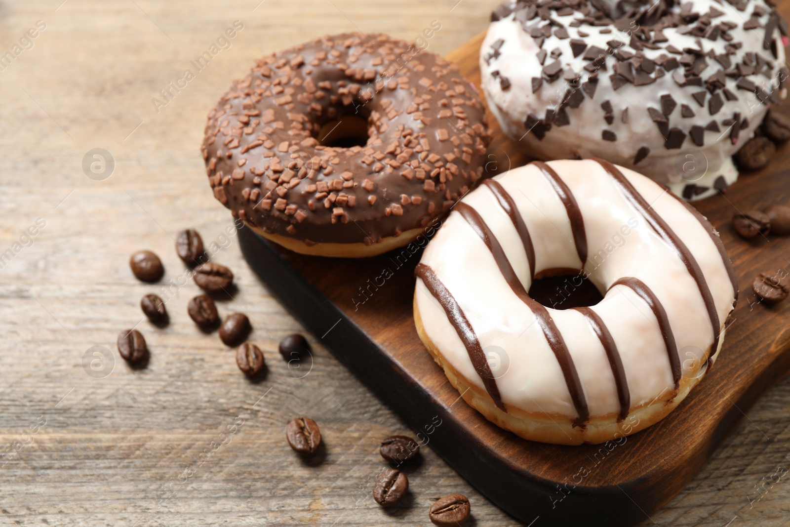 Photo of Yummy donuts with sprinkles on wooden table, closeup