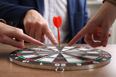 Photo of Business targeting concept. People pointing at dartboard at table, closeup