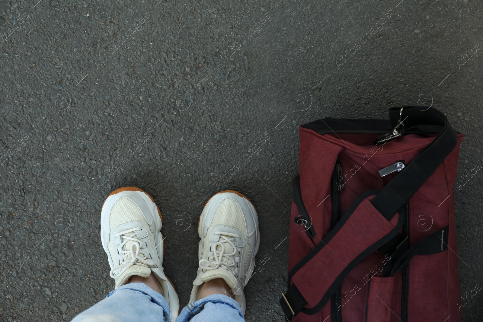 Photo of Woman with bag standing on asphalt, top view. Space for text