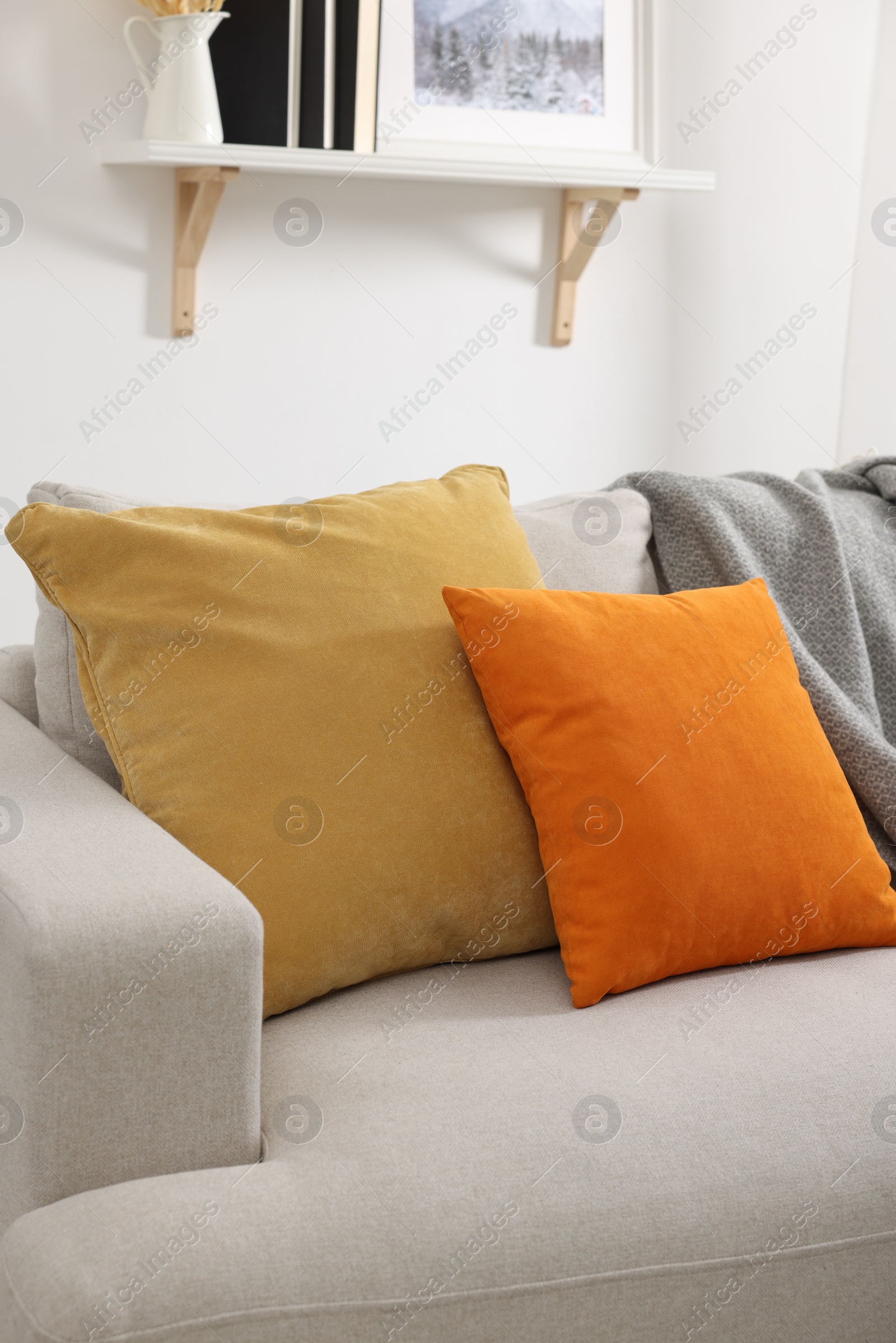 Photo of Soft pillows and blanket on sofa indoors