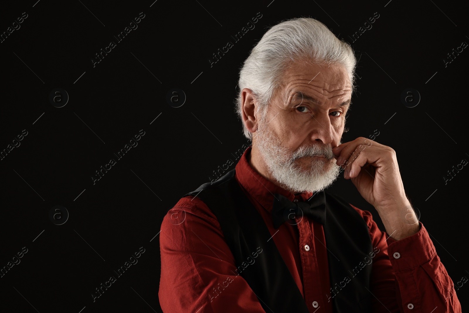 Photo of Senior man touching mustache on black background, space for text