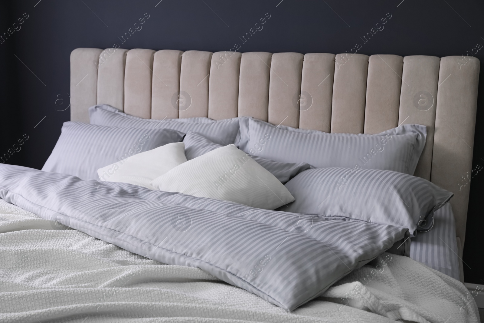 Photo of Comfortable bed with soft blanket and pillows indoors, closeup