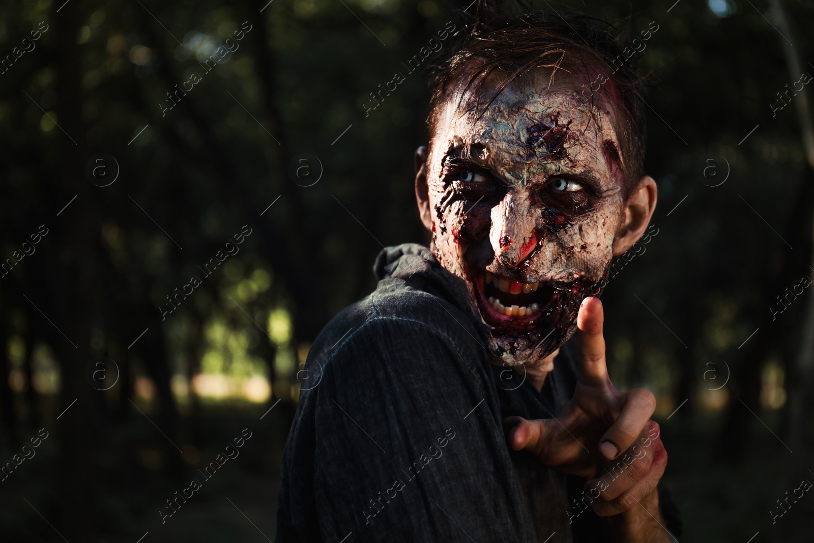 Photo of Scary zombie with bloody face outdoors. Halloween monster