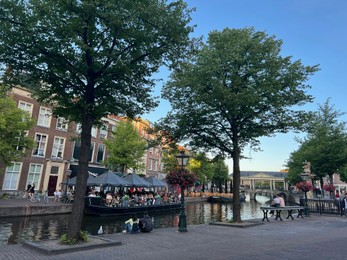 Leiden, Netherlands - August 1, 2022: Beautiful view of city street with outdoor cafe and trees along canal