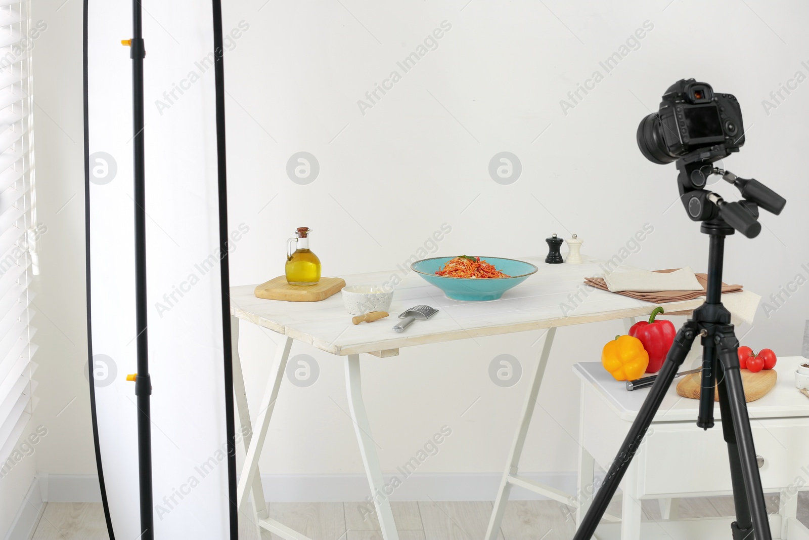 Photo of Professional equipment and composition with delicious spaghetti on white wooden table in studio. Food photography