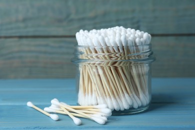 Many cotton buds on light blue wooden table