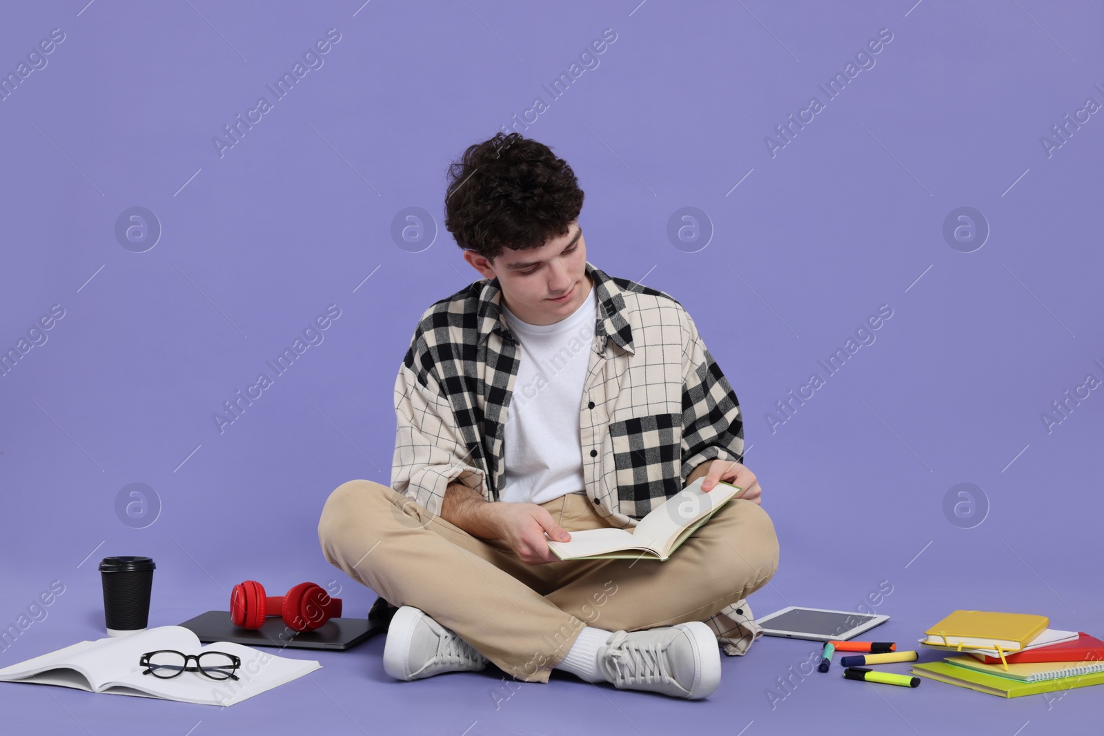 Photo of Portrait of student with notebook and stationery sitting on purple background