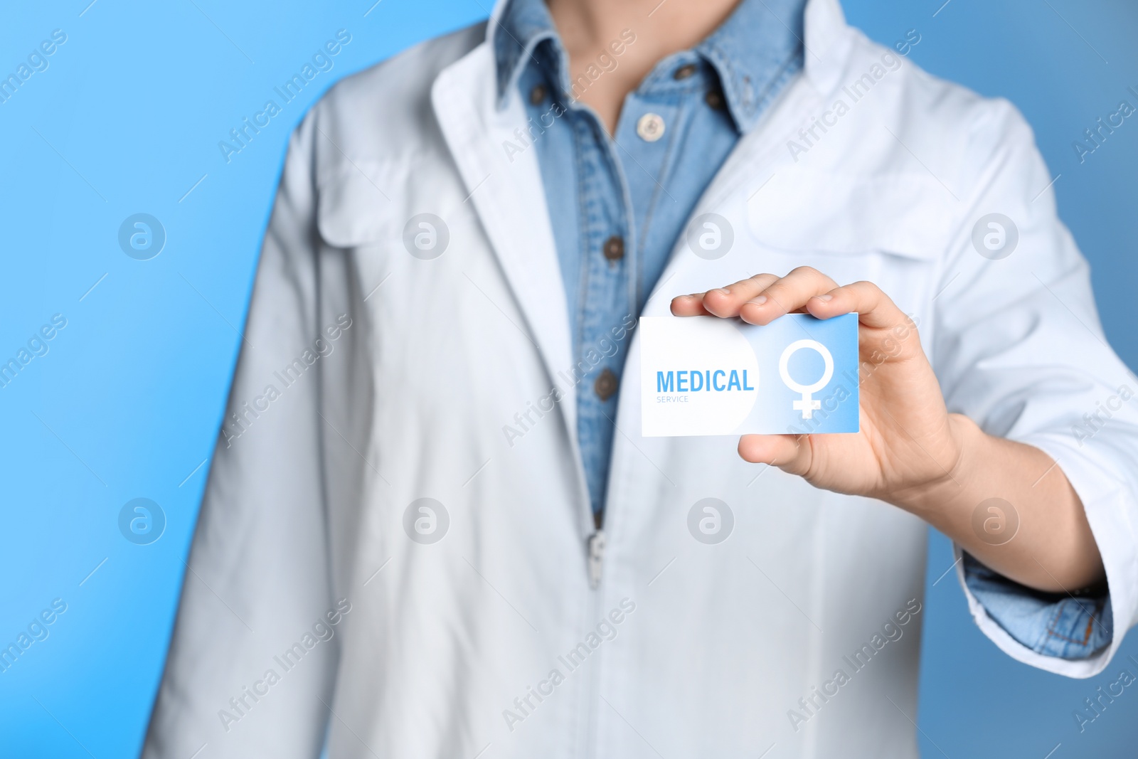 Photo of Doctor holding medical business card on color background, closeup. Women's health service