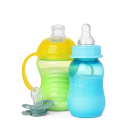 Feeding bottles with milk and pacifier on white background