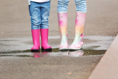 Mother and daughter wearing rubber boots on street, closeup