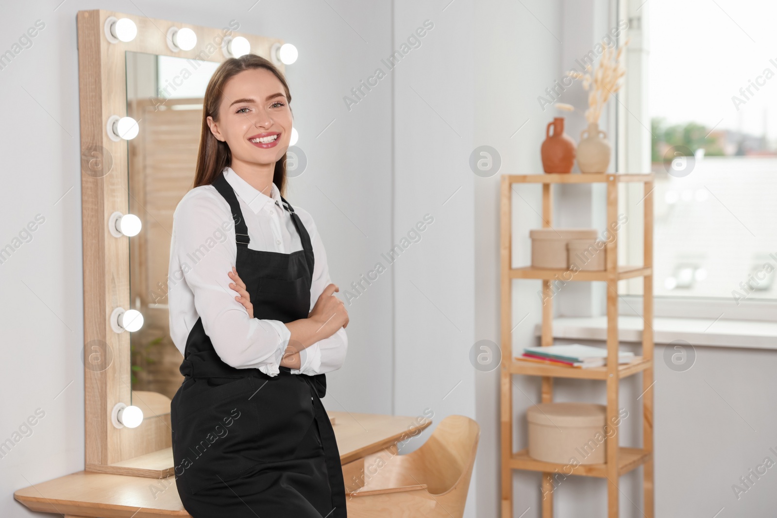 Photo of Portrait of professional hairdresser wearing black apron in beauty salon