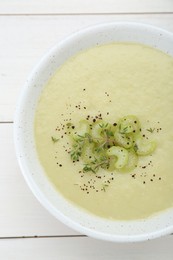 Bowl of delicious celery soup on white wooden table, top view