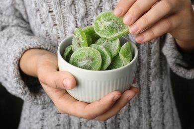 Woman holding bowl with slices of tasty kiwi, closeup. Dried fruit as healthy food