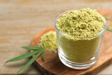 Glass of hemp protein powder on wooden table, closeup. Space for text