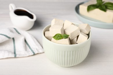 Photo of Delicious tofu with basil on white wooden table